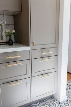 a kitchen with white cabinets and gold handles on the doors is pictured in this image