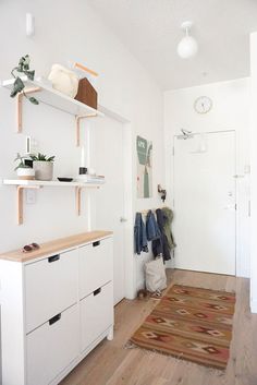 a room with white walls and wooden flooring, open shelving unit on the wall