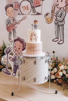 a wedding cake is sitting on a stand in front of a wall with musical instruments