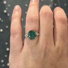 This rare and beautiful green emerald and diamond ring is perfect for any modern engagement! This oval cut emerald marquise diamond ring is finished in 14 karat yellow gold. Sleek modern in design. The center emerald reflects a rich sea green hue. Two (2) sparkling accent diamonds flank the center gemstone. Full of sparkle vibrant color. Finished on a classic 14 karat yellow gold band with a geometric gallery rail. Colored gemstone engagement rings add a personal touch to your special ceremony.