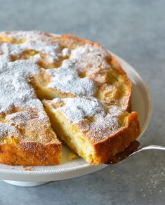 a cake with powdered sugar on top is sitting on a white plate next to a spoon