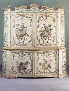 an antique painted cabinet with floral designs on the doors and drawers, possibly from france