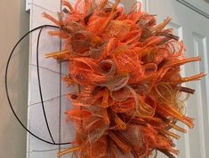 an orange mesh wreath hanging on the front door