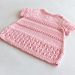 a pink knitted sweater sitting on top of a white table