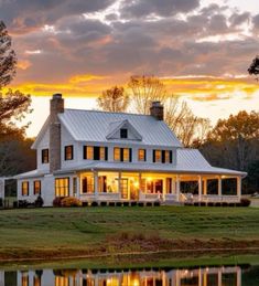 a large white house sitting on top of a lush green field next to a lake