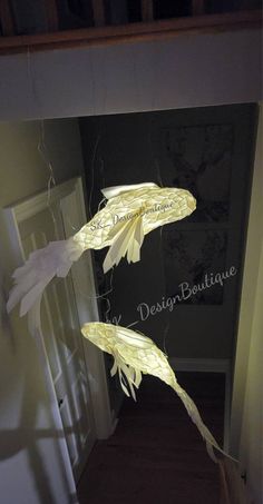 two paper flowers hanging from the ceiling in a hallway with stairs leading up to an open door