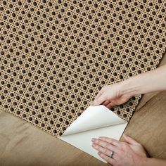 a woman is holding a piece of paper on top of a rug with holes in it