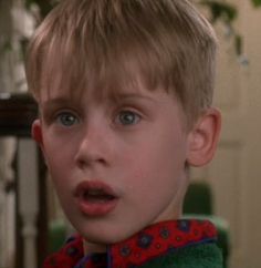 a young boy making a surprised face while standing next to an older woman in a living room