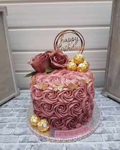 a pink and gold birthday cake with roses on top