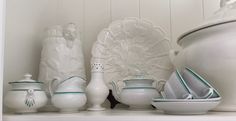 some white dishes and vases on a shelf