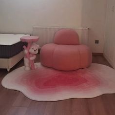 there is a pink chair and teddy bear on the floor in this room with white walls