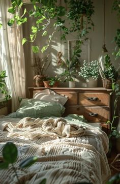 an unmade bed with green plants hanging from the ceiling and on top of it