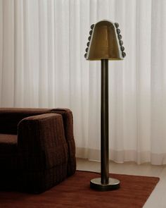 a floor lamp sitting on top of a brown rug next to a chair and window