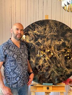 a man standing in front of a black and gold marbled round table with lights on it