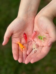 three hands holding small plastic toy animals in the palm of someone's outstretched hand