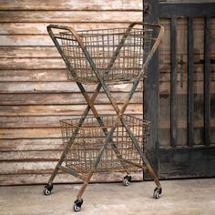 two metal baskets sitting on wheels next to a wooden wall with a barn door in the background