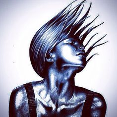 a woman with her hair blowing in the wind while wearing black and silver clothing,