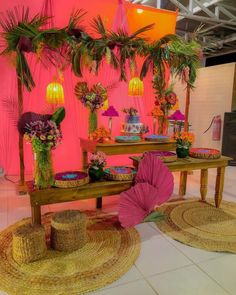 a table topped with lots of cakes and desserts under palm trees in front of a pink wall