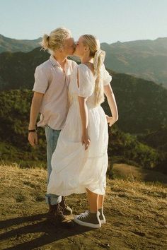 a man and woman kissing on top of a hill