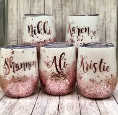 four wine glasses with glitter on them sitting on a table