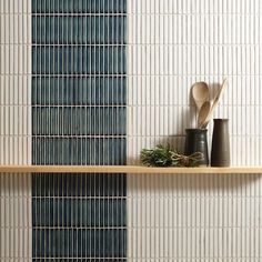 two wooden spoons are sitting on a shelf in front of a wall with blue and white tiles