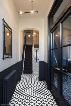 an entry way with black and white tile on the floor, stairs and mirror frames