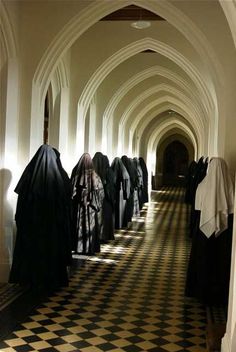 a long hallway with black and white checkered flooring on both sides, lined up with cloaks