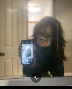 a woman taking a selfie in front of a mirror with her cell phone up to her face