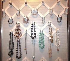 a wall mounted jewelry rack with several different necklaces and rings hanging on it's sides