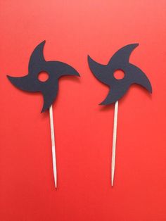 two black masks sitting on top of toothpicks in front of a red background