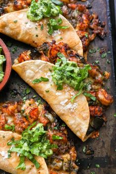 three pita breads on a baking sheet with salsa and cilantro