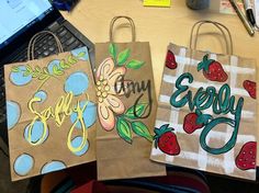 three paper bags with designs on them sitting on a desk next to a laptop computer