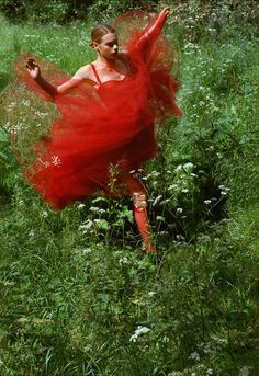 a woman in a red dress is running through the grass