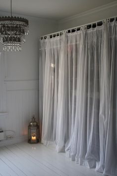 a white room with curtains and a candle