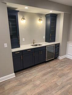 an empty kitchen with blue cabinets and white counter tops, wood flooring and gray walls