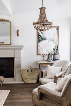 a living room filled with furniture and a chandelier hanging over the fire place