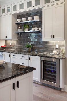 a kitchen with marble counter tops and white cabinets