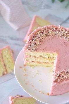 a cake with pink frosting and gold sprinkles on a white plate