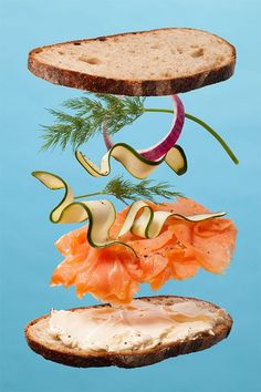 a sandwich with salmon, cucumber and lettuce falling into the air