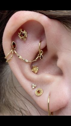 an ear with three different types of piercings on it's sides and one is gold