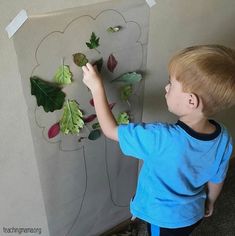 a young boy painting leaves on a wall