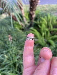 someone is holding their finger up to show the ring on his thumb and palm tree in the background