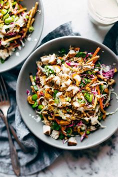 two bowls filled with salad on top of a table next to forks and napkins