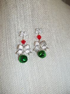 "Bells and Bows Drop Dangle Earrings Christmas Holiday Secret Santa Hostess Gift Simple yet striking design Lovely silver bows are incorporated into this chandelier style earring Smaller bow is the base for these post/stud earrings Embellished with a red crystal then a larger matching bow holds a real jingle bell Bows are aluminum Crystal is glass Bell is colored aluminum Earring length measures 1 3/8\" Earring width measures 5/8\" (widest point is larger bow) Comes in a festive gift box for instant gift giving" Christmas Celebration Jewelry Drop Earrings, Christmas Celebration Drop Earrings Jewelry, Red Jewelry For Christmas Holiday, Festive Holiday Jewelry With Dangle Shape, Festive Holiday Dangle Jewelry, Red Jewelry For Christmas Celebration, Christmas Dangle Jewelry For Celebration, Dangle Jewelry For Christmas Celebration, Christmas Celebration Dangle Jewelry