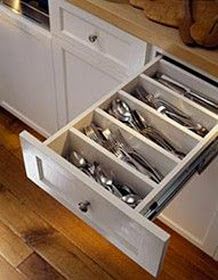 an open drawer in the middle of a kitchen with silverware and utensils