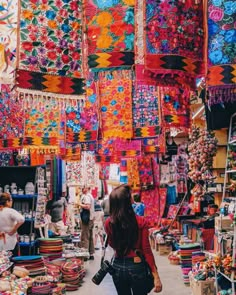 a woman walking through a market filled with lots of colorful items