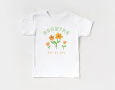 Our tees are made using the highest quality cotton for a soft touch that is super comfortable from first wear! With fun and whimsical graphics, our shirts are the perfect base layer for your kids stylish wardrobe. Fabric Breakdown: 100% Airlume combed and ring-spun cotton Sustainability:  100% No Sweatshops and Eco- friendly. W.R.A.P certified Features:  Side seamed. Retail fit. Unisex sizing. Care Instructions: Turn Inside Out Machine Wash Cold Using Gentle Cycle Do Not Bleach / Fabric Softener Dry Flat. Do not Dry Clean Do Not Iron On Print   Notes: Colors Will Vary Slightly Due to Lighting And/Or Monitor Settings Listing is only for the shirt other products seen in photos are for styling purposes only Sizing: See Photos for Size Chart Thank You For Supporting Our Small Business!See more Playful Cotton T-shirt For Spring, Cute Floral Graphic Print Tops, Playful Pre-shrunk Shirt For Spring, Cute Pre-shrunk Spring T-shirt, Cute Pre-shrunk T-shirt For Spring, Baby Tee Shirts, Girl Shirts, Flower Graphic, Day By Day