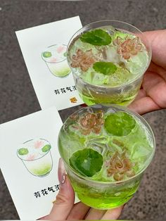 two glasses filled with green drinks sitting next to each other