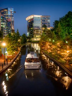 a boat traveling down a river in the middle of a city with tall buildings on either side