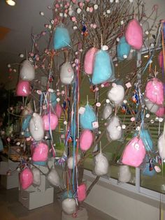 a tree with pink, blue and white ornaments hanging from it's branches in front of a window